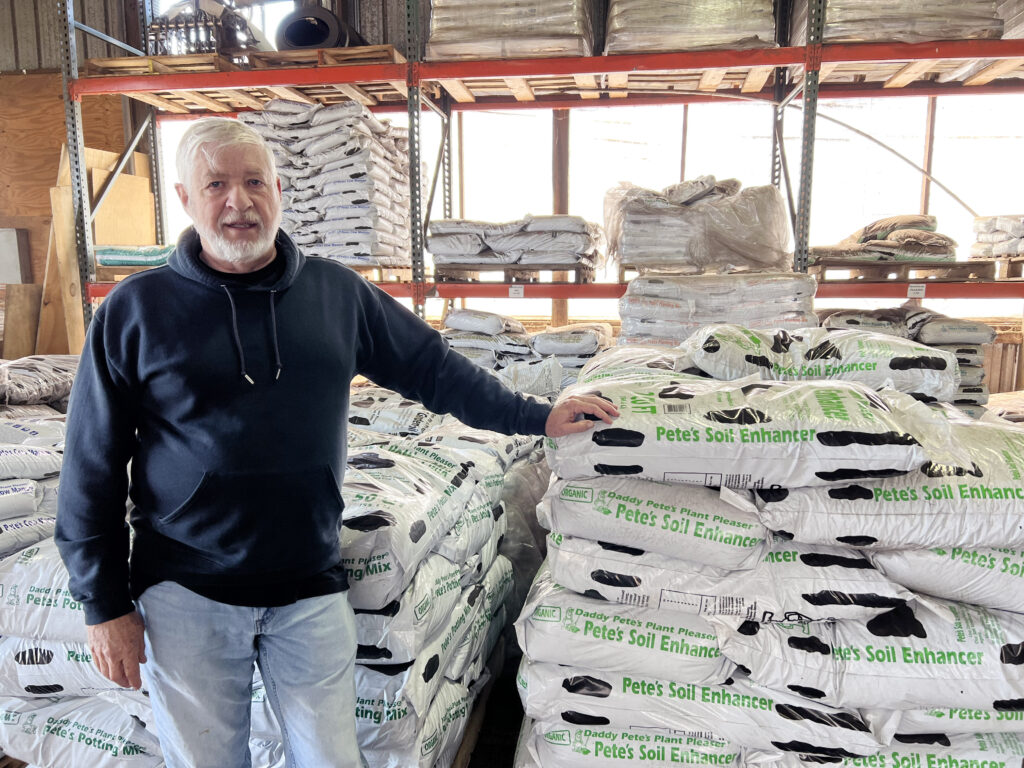 man stands next to bagged compost product.